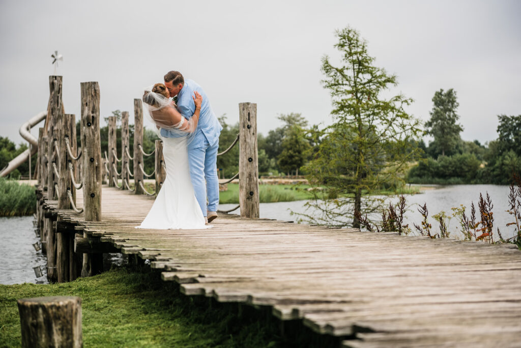 Bruid en bruidegom geven elkaar een innige kus op een houten brug